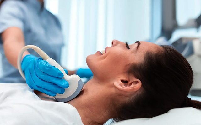 Patient receiving an ultrasound on the neck, with a medical professional performing the procedure.
