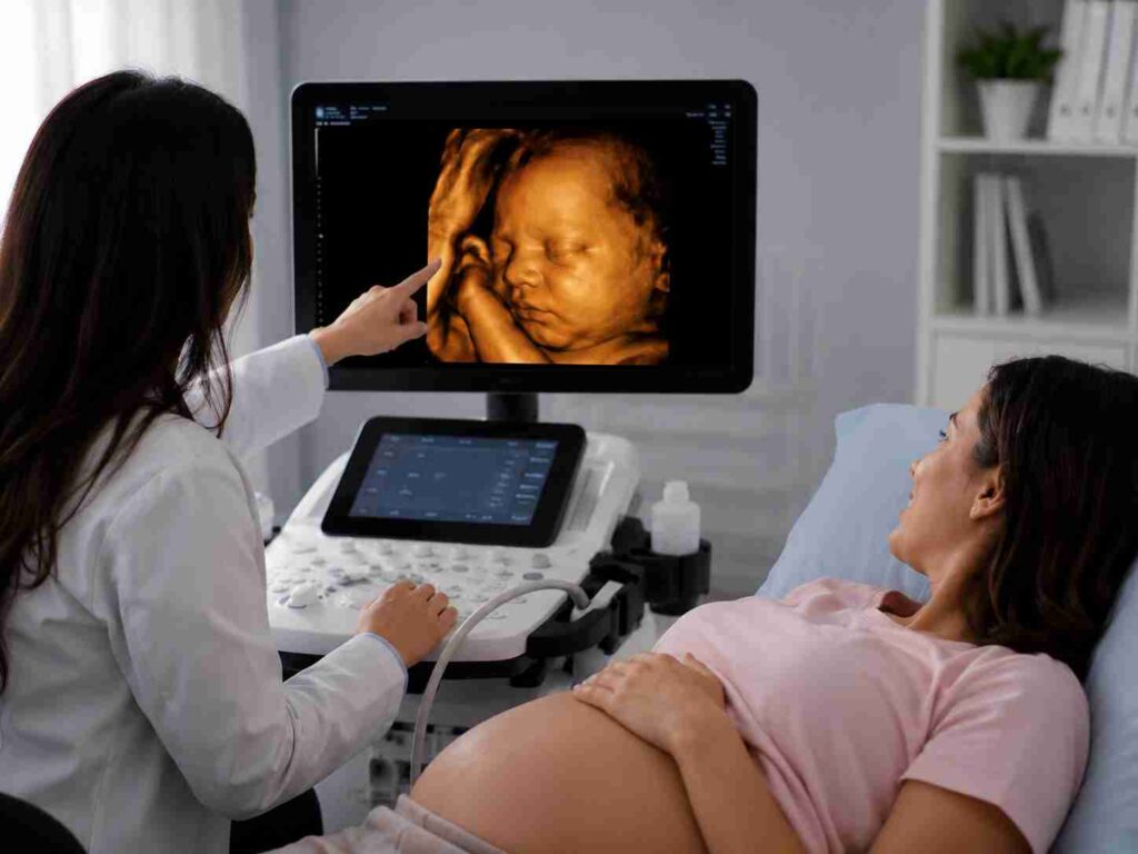 Pregnant woman undergoing an ultrasound scan while a doctor reviews the baby's 3D image on the monitor during prenatal evaluation.